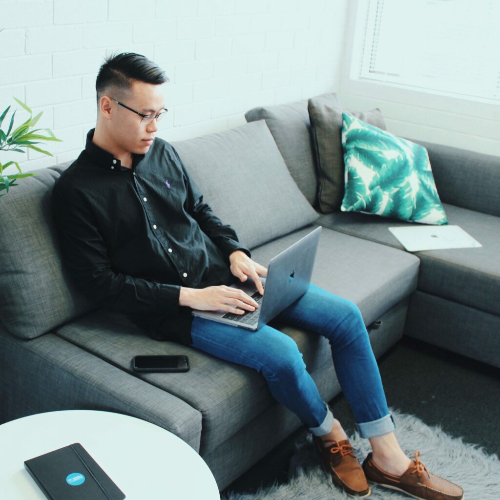 Ryan Khong Sitting on a couch working at Word of Mouth Agency in Perth